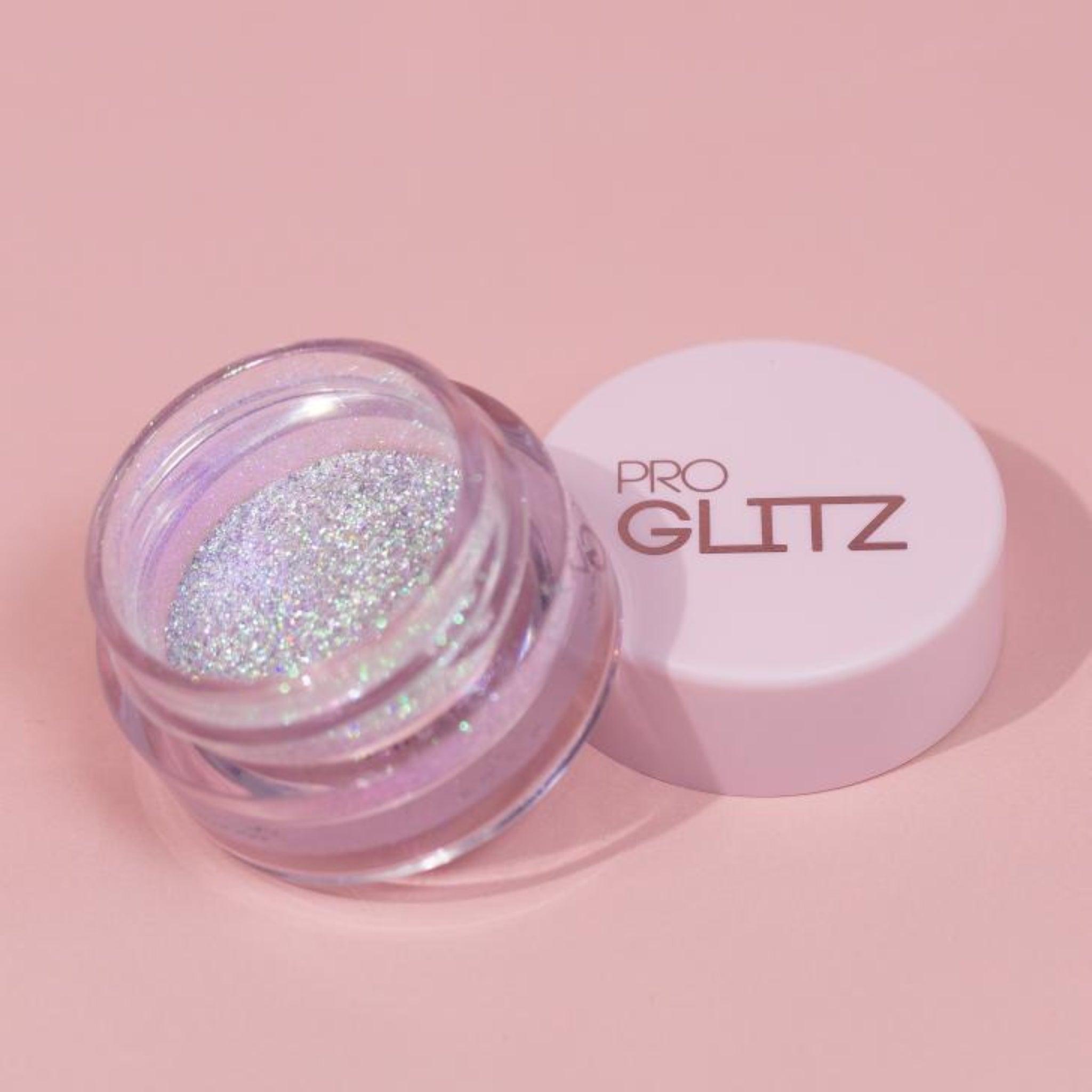 Holographic Duochrome eyeshadow. A shimmering, multi-dimensional makeup product featuring colour shifting pigments that transition between hues of purple and pink with a rainbow sparkle. Radiant, prismatic effect.